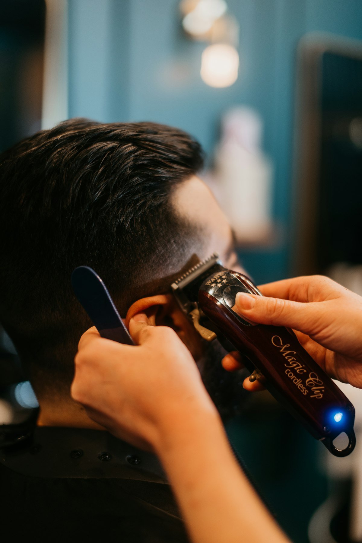 Barber trimming around the ear with a clipper
