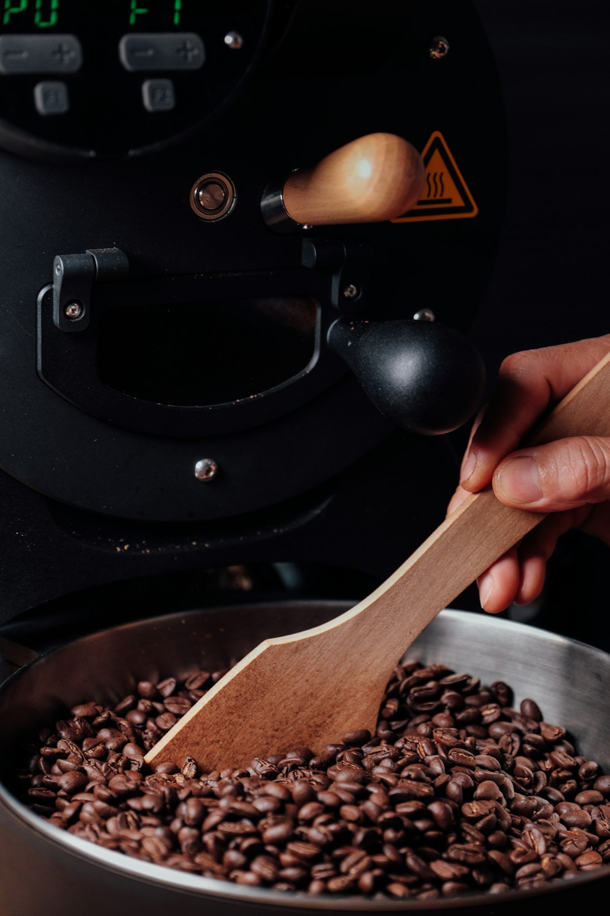 Hand at the roaster drum with a wooden trier