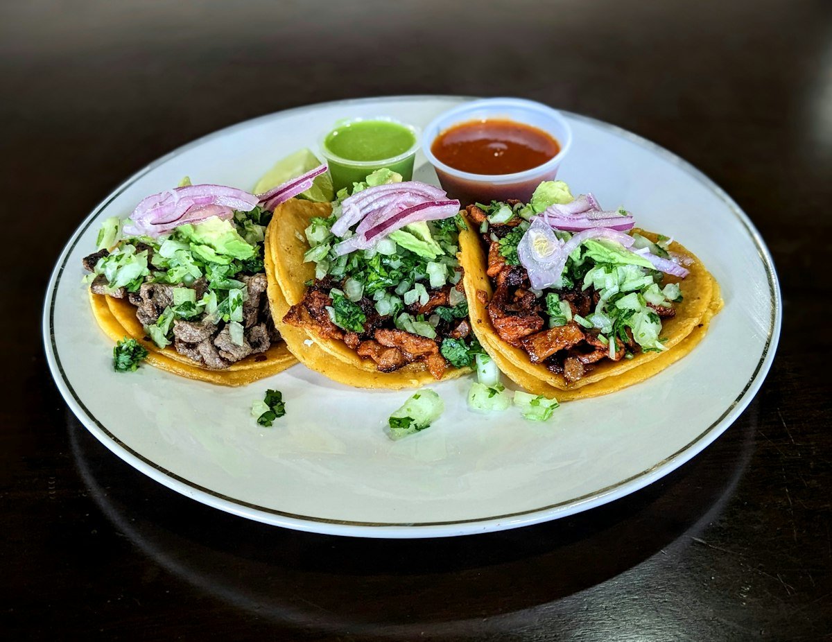 A plate of tacos served with bowls of salsa