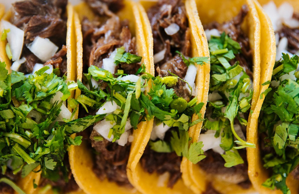 Three tacos topped with white onion and cilantro